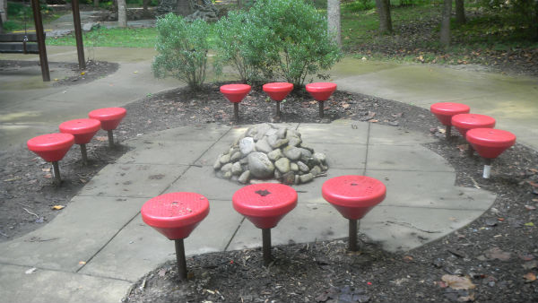 Red stools around a rock structure in Warriors' Path State Park.